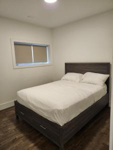 Lakeview Breaktrail Stays في Crosby Island: غرفة نوم بها سرير بملاءات بيضاء ونافذة