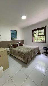 ein Schlafzimmer mit Bett, Schreibtisch und Fenster in der Unterkunft Casa de Praia - 4 quartos Centro in Bombinhas + 8 Fotos