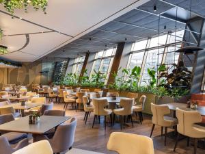 um restaurante com mesas, cadeiras e plantas em Mercure Sofia City em Sófia