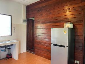 a kitchen with a refrigerator and a wooden wall at Nazo Boutique Bungalows in Wok Tum