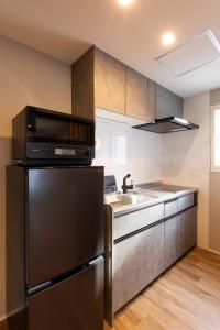 a kitchen with a black refrigerator and a sink at The Residence Sapporo - すすきの駅から徒歩6分 - in Sapporo
