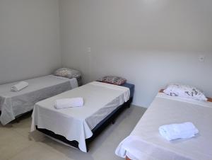 three beds in a room with white walls at Apartamentos modernos próximos a tudo in São Gabriel