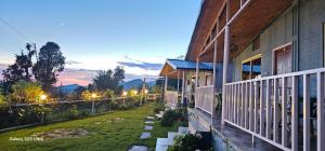 uma casa com uma varanda com um quintal em Namaha hotel and cottages em Kanatal