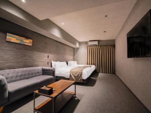 une chambre d'hôtel avec un lit et un canapé dans l'établissement Randor Hotel Namba Osaka Suites, à Osaka