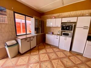 a small kitchen with white cabinets and appliances at Hostal Nuevo Sol y Viento in San Pedro de Atacama