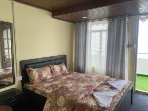 a bedroom with a bed and a large window at 12 Degree in Takdāh