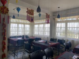 a dining room with tables and chairs and windows at 12 Degree in Takdāh