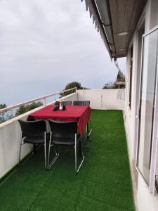 a table and chairs on a balcony with green grass at 12 Degree in Takdāh