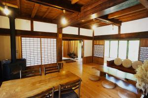 a living room with a table and chairs and a fireplace at 農ある暮らしの宿 古民家 天地 in Minamiizu