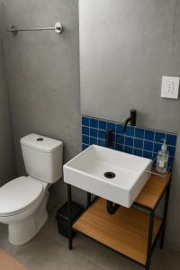 um banheiro com uma pia branca e um vaso sanitário em Pousada Ideal - Estúdios com Cozinha & Terraço Exclusivo - Suítes Econômicas no Guarujá