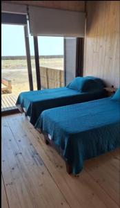 twee bedden in een kamer met een raam bij Sirena Lodge in De Cauquenes