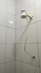 een douche met een slang aan een witte betegelde muur bij Casa Cariri Mobiliada com 2 Quartos e 2 Camas in Juazeiro do Norte