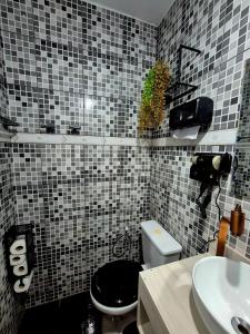 a bathroom with a black and white tiled wall at Studio completo e aconchegante com vaga de garagem in Campinas +18 photos