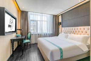 ein Hotelzimmer mit Bett, Schreibtisch und Fernseher in der Unterkunft Manyueju Hotel  + 22 Fotos