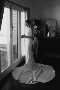 a bride standing next to a window looking at her phone at The Retreat Port Stephens in Anna Bay +91 photos