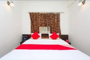 a bedroom with a white bed with red pillows at Hotel Vijay Palace in Bhopal