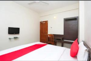 a bedroom with a bed with red pillows and a tv at Hotel Vijay Palace in Bhopal +1 photo