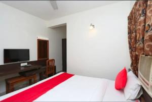 a bedroom with a bed with a desk and a television at Hotel Vijay Palace in Bhopal