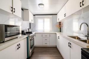 a kitchen with white cabinets and stainless steel appliances at Overlooking a Park - A sunny escape in Rooty Hill
