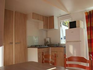 Mobil home pour 8 avec terrasse à Payrac - API-1-52-1222 في Payrac: مطبخ مع ثلاجة بيضاء وخزائن خشبية