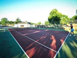 Mobil home pour 8 avec terrasse à Payrac - API-1-52-1222 في Payrac: شخص يلوح بمضرب تنس في ملعب التنس