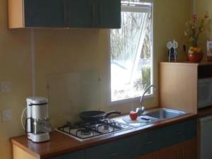 Mobil-home confortable pour 5 pers. en camping à Payrac - API-1-52-1221 في Payrac: مطبخ مع موقد ومغسلة ونافذة