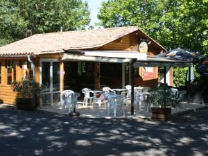 Mobil-home confortable pour 5 pers. en camping à Payrac - API-1-52-1221 في Payrac: مطعم بطاولات بيضاء وكراسي امام مبنى