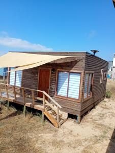 Cabañas Campo y Mar في Los Corrales: كابينة خشبية مع شرفة ومظلة