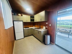 a kitchen with a white refrigerator and a window at Harbour Heights Cabins in Athenree
