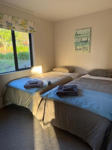 Dos camas en una habitación con ventana. en Cosy Country Private Cottage with views, en Harapepe