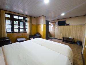 a bedroom with a large white bed and a tv at Veronica Alpina Mountain View Home in Darjeeling