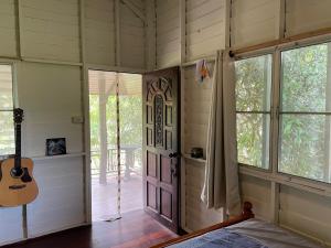 a bedroom with a door and a guitar in a room at Nazo Boutique Bungalows in Wok Tum