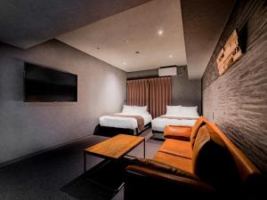 une chambre d'hôtel avec deux lits et un canapé dans l'établissement Randor Hotel Namba Osaka Suites, à Osaka