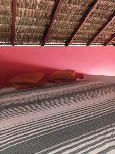 un letto con 2 cuscini e una parete rosa di Chalé pé na areia e vista Mar a Ilhéus