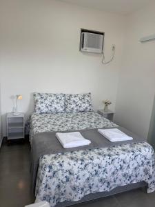a small bedroom with a bed with a floral bedspread at Pousada Oito Mares in Arraial do Cabo
