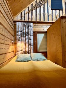 a bed in a wooden room with a window at Authentic Log Cottage with Hot Tub in Ranua