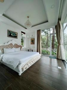 a bedroom with a white bed and a large window at Lan Anh Villas Resort in Da Lat +176 photos