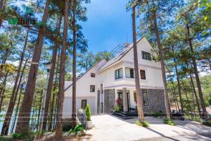 a white house with trees in front of it at Lan Anh Villas Resort in Da Lat