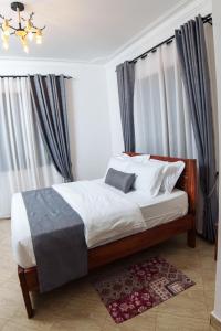 a bedroom with a large bed with curtains and a chandelier at Lavista Place in Jinja
