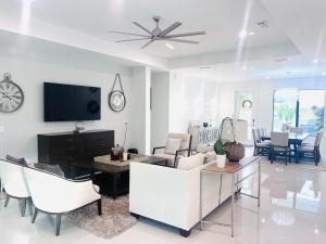 a living room with white furniture and a tv at Tropical Oasis in Naples