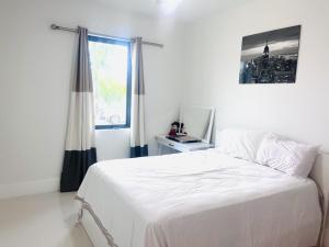 a white bedroom with a bed and a window at Tropical Oasis in Naples