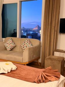 Una sala de estar con un sofá y una ventana grande. en New LA Veranda Pyramids Inn, en El Cairo