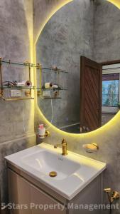 La salle de bains est pourvue d'un lavabo et d'un miroir rond. dans l'établissement Serenity Sands Villa, Beachfront and Mountain View, à Chaloklum