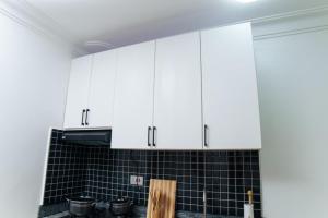 a kitchen with white cabinets and black tiled wall at Lavista Place in Jinja +158 photos