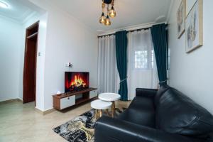 a living room with a black leather couch and a tv at Lavista Place in Jinja