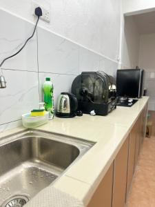 eine Küchentheke mit Spüle und Mikrowelle in der Unterkunft 3 Bedrooms Single Storey Terrace at Taman Inderawasih ,12mins to Penang Bridge , 5mins to Sunway Carnival Mall in Butterworth + 3 Fotos