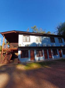 a large white house with a staircase in front of it at Orquídeas De La Selva in Puerto Iguazú