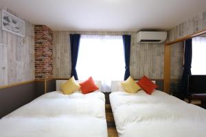 two beds in a small room with a window at Prosper 6th bldg in Nagoya