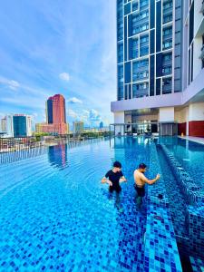 Twee mannen knielen in het water van een zwembad. bij Chambers Klcc Suites Esten in Kuala Lumpur