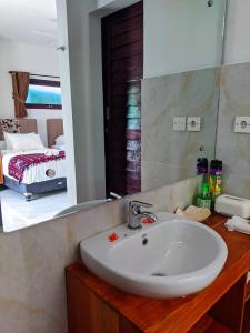Un baño con lavabo, espejo y cama. en Villa Collard, en Senggigi 